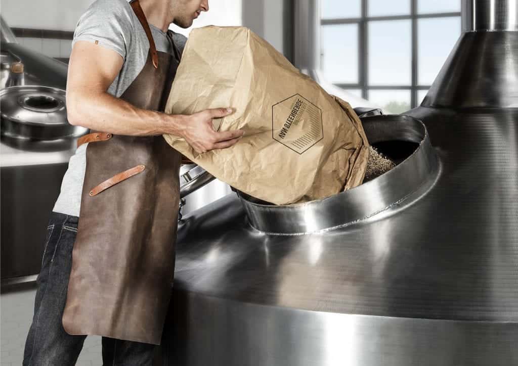 Foto van man die graan giet in brouwketel