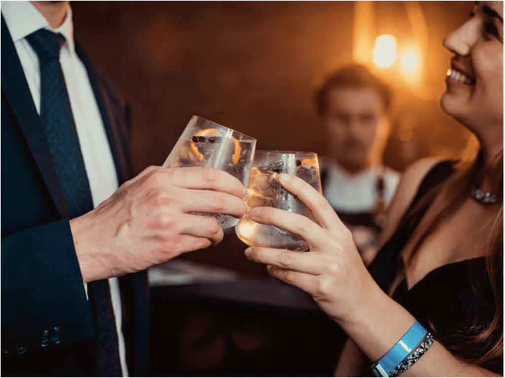 Professioneel geklede man en vrouw klinken met cocktail op privé event