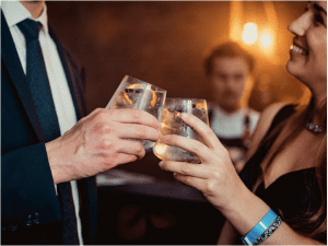 Professioneel geklede man en vrouw klinken met cocktail op privé event
