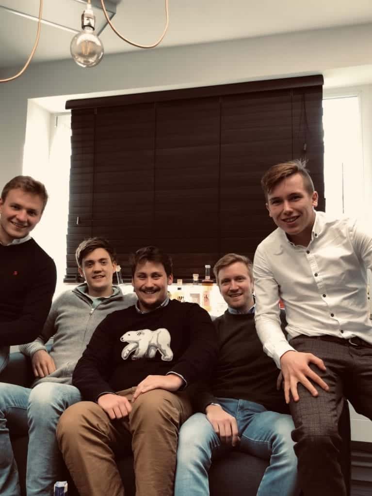 Vijf jonge gasten op sofa kijken naar de camera