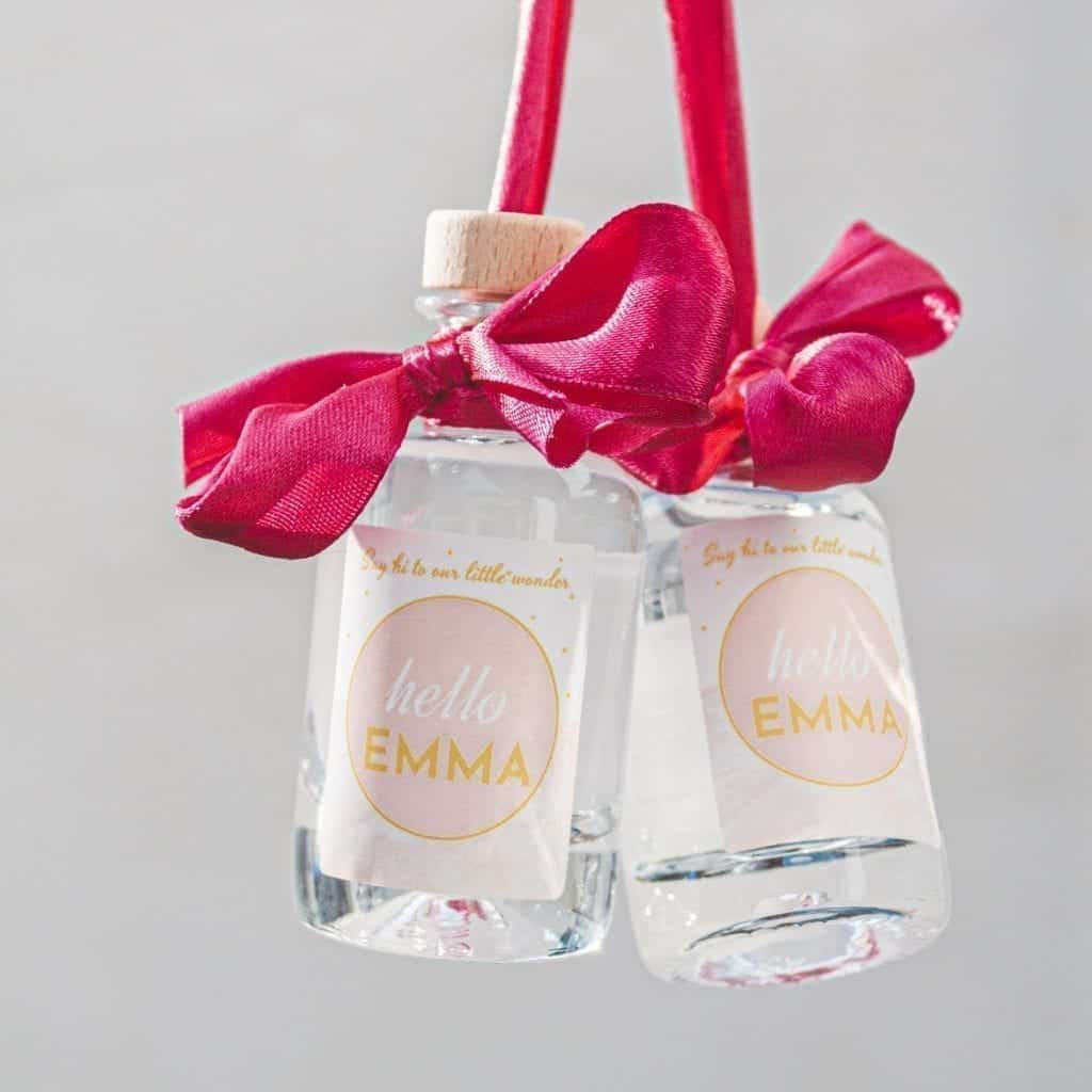 Foto van 2 zwevende miniflesjes met roze etiket met opschrift "hello emma"
