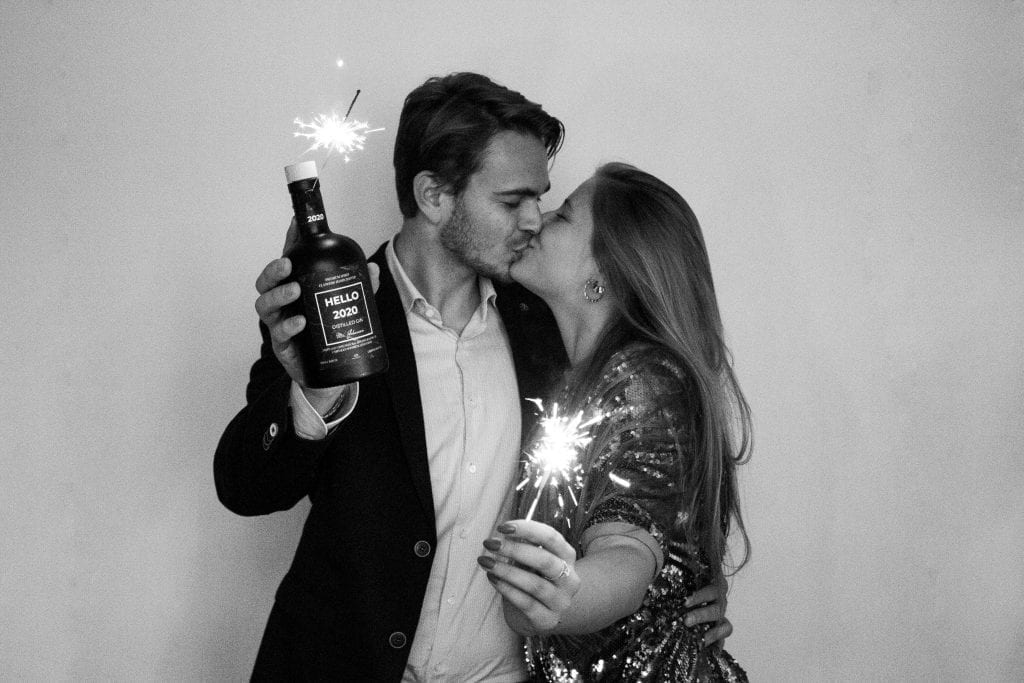 Foto van kussend koppels die gepersonaliseerde fles gin vasthouden en vuurwerk