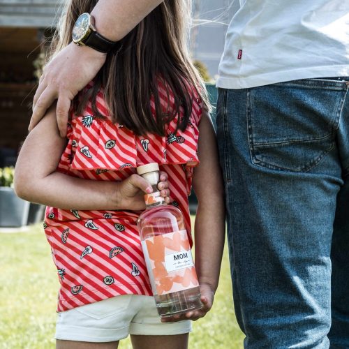 Kindje die fles gin aan mama geeft als moederdag cadeau